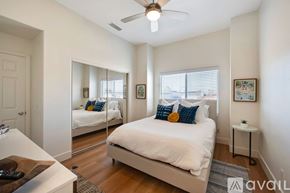 Huntington Beach house for rent - A bedroom with a bed, a mirror, a ceiling fan, and a small side table.