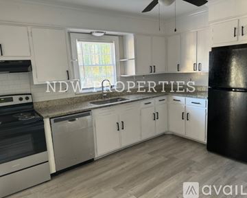 Wilson apartment for rent - A kitchen with white cabinets and a black refrigerator is available for rent.