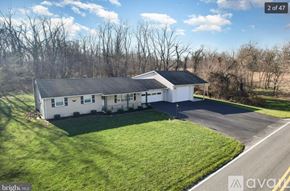 Carlisle apartment for rent - A white house with a black roof is surrounded by a grassy lawn and trees.