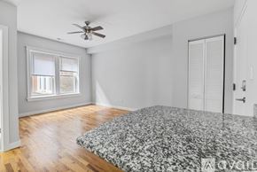 Chicago apartment for rent - A bedroom with a bed, a ceiling fan, and a window with blinds.