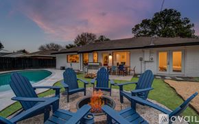 Houston house for rent - A house with a pool and four chairs around a fire pit.
