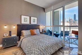 Chicago apartment for rent - A bedroom with a large bed and a view of the city skyline.