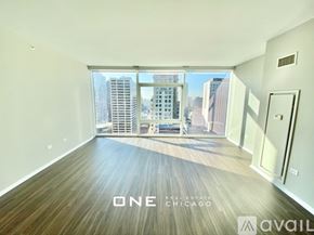 Chicago apartment for rent - A spacious room with wooden flooring and a view of the cityscape outside the window.