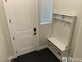 Lehi apartment for rent - A white door with a black handle is next to a white shelf with hooks.