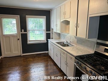 Tulsa house for rent - A kitchen with white cabinets and a stove top oven.