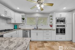 Murfreesboro house for rent - A kitchen with white cabinets and a marble countertop.
