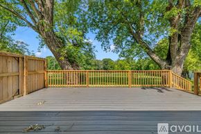 Murfreesboro house for rent - A wooden deck with a railing and trees in the background.