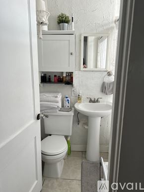 Tampa apartment for rent - A white bathroom with a toilet, sink, and mirror.