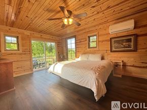 Thompsonville house for rent - A bedroom with wooden walls and a bed in the center.