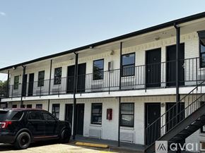 Houston apartment for rent - A black SUV is parked in front of a white building with black railings.