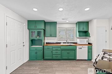 Grants Pass house for rent - A kitchen with green cabinets and a white dishwasher.