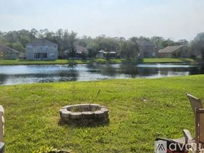 Orlando house for rent - A fire pit sits in the middle of a grassy field with a lake and houses in the background.