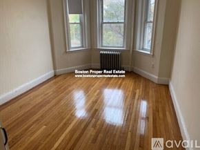 Boston apartment for rent - A room with wooden flooring and a window overlooking a tree-filled yard.