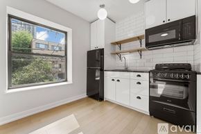 Chicago apartment for rent - A kitchen with black appliances and white cabinetry.