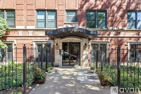 Chicago apartment for rent - The entrance to a brick building with a black gate and a sign that reads "The Windale.".