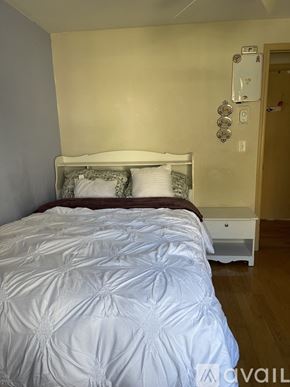 Jacksonville apartment for rent - A bed with a white comforter and pillows in a room.