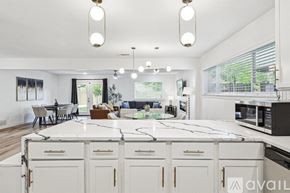 Irving house for rent - A modern kitchen with white cabinets and a marble countertop.