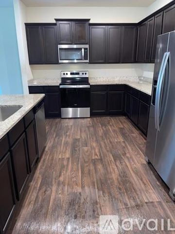New Braunfels house for rent - A kitchen with dark wood cabinets and a stainless steel refrigerator.