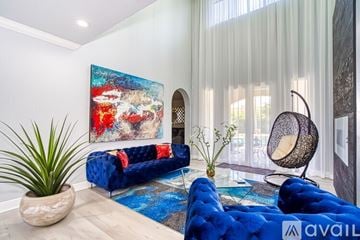 Hialeah house for rent - A blue couch sits in a living room with a large painting on the wall.