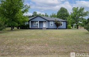 Murfreesboro house for rent - A blue house with a white door and windows is surrounded by green trees.