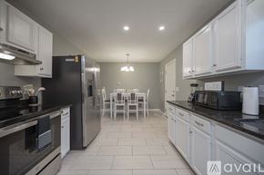 Murfreesboro house for rent - A kitchen with white cabinets and black appliances.