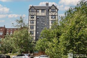 Chicago apartment for rent - A tall building with a mix of grey and white sections is surrounded by green trees and parked cars.