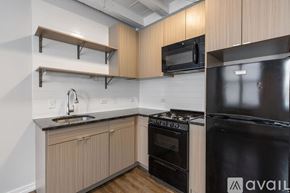 Chicago apartment for rent - A kitchen with a black stove and oven, wooden cabinets, and a black microwave.