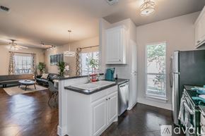 Fort Worth house for rent - A kitchen with white cabinets and a black refrigerator.