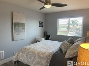 Carlsbad condo for rent - A bedroom with a bed, a ceiling fan, and a painting on the wall.