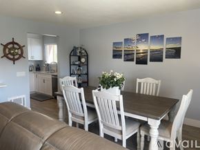 Carlsbad condo for rent - A dining room with a table set for four and a ship's wheel on the wall.