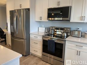 Carlsbad condo for rent - A kitchen with a stainless steel refrigerator and oven, white cabinets, and a wooden floor.