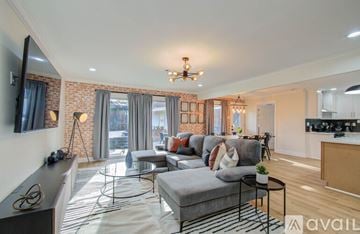 Houston house for rent - A living room with a grey couch and a chandelier.