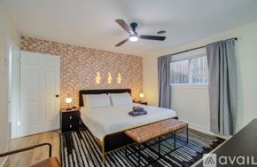 Houston house for rent - A bedroom with a brick wall and a bed with a wooden headboard.