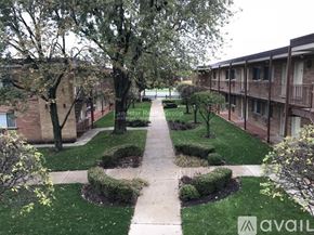 Morton Grove apartment for rent - A courtyard with a pathway and greenery in front of apartment buildings.