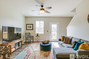 Greenville townhouse for rent - A living room with a grey couch, a wooden entertainment unit, and a rug.