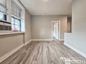 Evanston apartment for rent - A spacious room with wooden flooring and a large window with blinds.