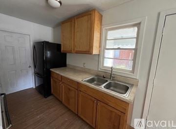 North Little Rock house for rent - A kitchen with wooden cabinets and a black fridge.