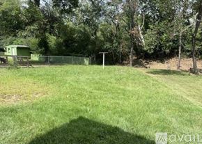North Little Rock house for rent - A green field with a fence and a tree in the background.