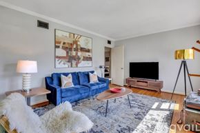 Savannah apartment for rent - A living room with a blue couch, a wooden coffee table, and a large painting on the wall.