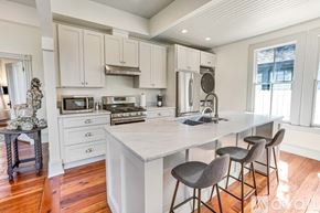 Savannah house for rent - A kitchen with a white island and grey barstools.
