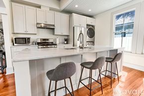 Savannah house for rent - A kitchen with white cabinets and a white countertop with two grey barstools.
