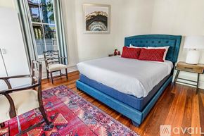 Savannah house for rent - A bedroom with a blue headboard bed and a red rug.