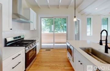 Brookline apartment for rent - A modern kitchen with white cabinets and a black stove top.