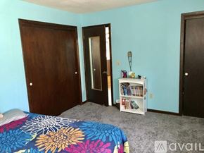 Ithaca house for rent - A bedroom with a bed, a bookshelf, and two doors.