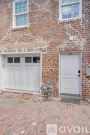 Savannah apartment for rent - A white garage door is on the right side of a brick building.