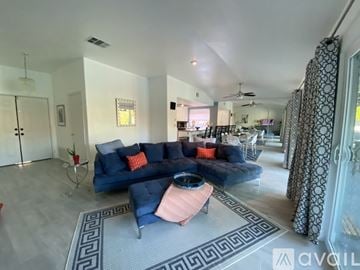 Palm Springs apartment for rent - A living room with a blue couch and a pink ottoman.