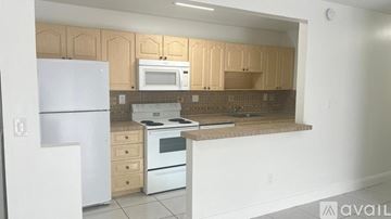 Doral apartment for rent - A kitchen with a white refrigerator, white microwave, and white oven.