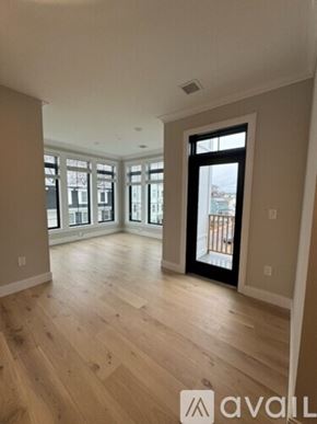 Boston apartment for rent - A spacious room with wooden floors and a large window.