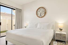 Scottsdale condo for rent - A bedroom with a large bed, a round decorative piece on the wall, and a window with a view of the outside.