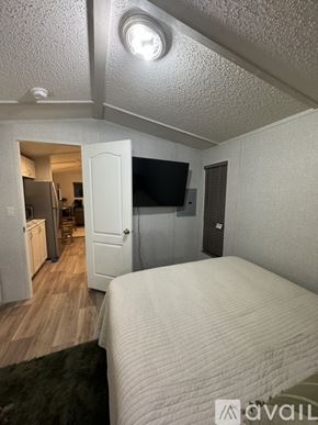 Horse Cave house for rent - A bedroom with a bed, a television, and a refrigerator in the kitchen area.